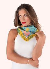 Woman wearing a colorful blue and yellow scarf with floral patterns on a white background.