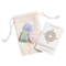 Beige pouch with rose quartz, blue lace agate, and amazonite lying on top of it. A card with the Cast of Stones logo and the text "Calming & Anti-Anxiety Crystals and Stones" sits next to it against a white background.