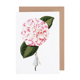 White card with a watercolor painting of a small woman holding an oversized pink and white camelia flower.