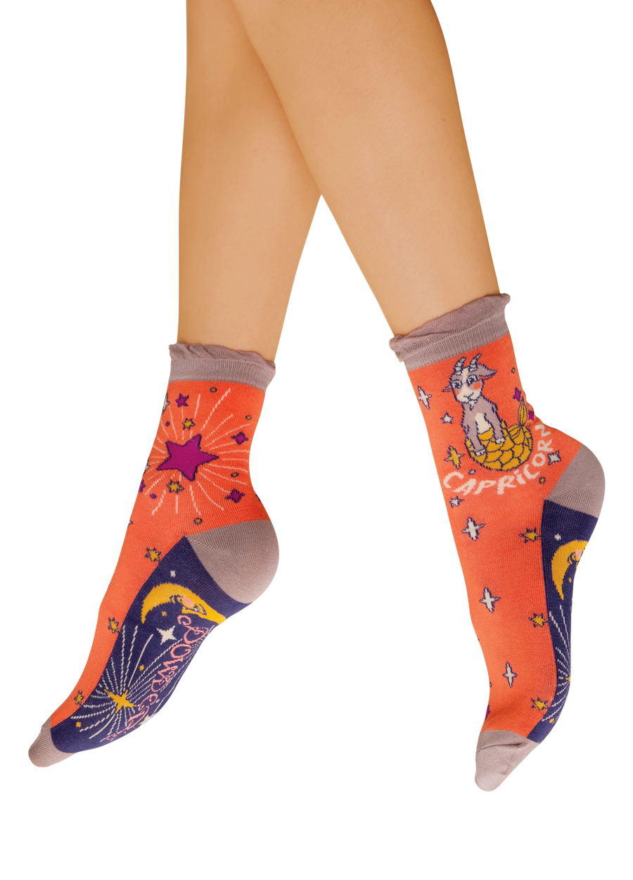 Orange blue and beige color block socks with a sea-goat. "Capricorn" is written underneath the sea-goat, with celestial elements around the socks.