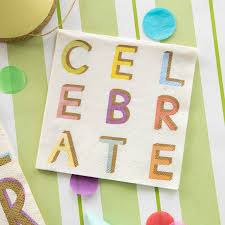 Cocktail napkin with "CELEBRATE" spelled out in colorful block letters, placed on a green and white striped background with confetti.