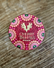 Red round chocolate box with intricate gold, green and pink details, that reads "Cherry Truffles". Set in front of a wood background. 