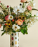 Bouquet in a vase with an illustrated bug pattern on a neutral background.