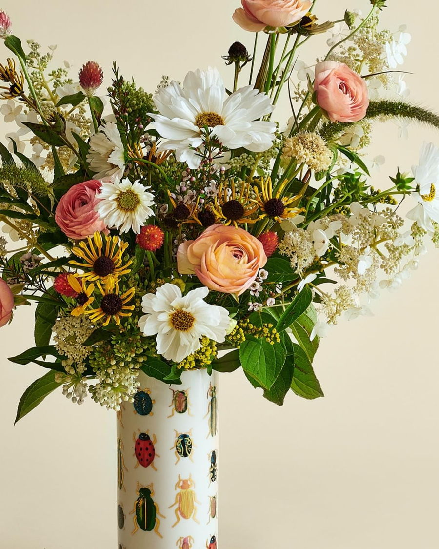 Bouquet in a vase with an illustrated bug pattern on a neutral background.