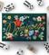 Dark green dominoes box with embroidered flowers, and dominoes scattered around the box. 