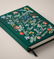 Close up of dark green, floral embroidered journal with the text "There are always flowers for those who want to see them. -Matisse"