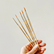 Hand holding a set of paintbrushes against a plain cream. background