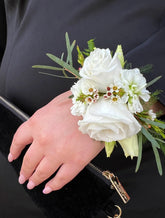 Corsage made with white flowers, against a black jacket. 