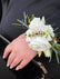 Corsage made with white flowers, against a black jacket. 