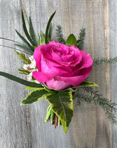 Boutonniere made with hot pink flower and greenery.