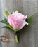 Boutonniere made with light pink flower and greenery.