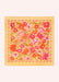 A square scarf with a vibrant floral pattern, featuring orange, pink, and red flowers with green leaves on a pale yellow background, laid flat against a light cream backdrop.