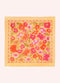 A square scarf with a vibrant floral pattern, featuring orange, pink, and red flowers with green leaves on a pale yellow background, laid flat against a light cream backdrop.