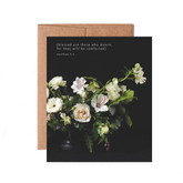 Black greeting card with a white and green floral arrangement and a quote saying "Blessed are those who mourn, for they will be comforted. Matthew 5:4."