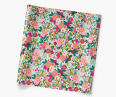 A square sheet of wrapping paper featuring a colorful, dense floral print on a light blue background, shown at an angle against a plain white background.