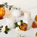 Two white candles surrounded by gardenia flowers and amber pieces on a white table.