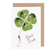 White card with watercolor painting of a small manholding an oversized four leaf clover. Cursive red text below reads "Good Luck". 
