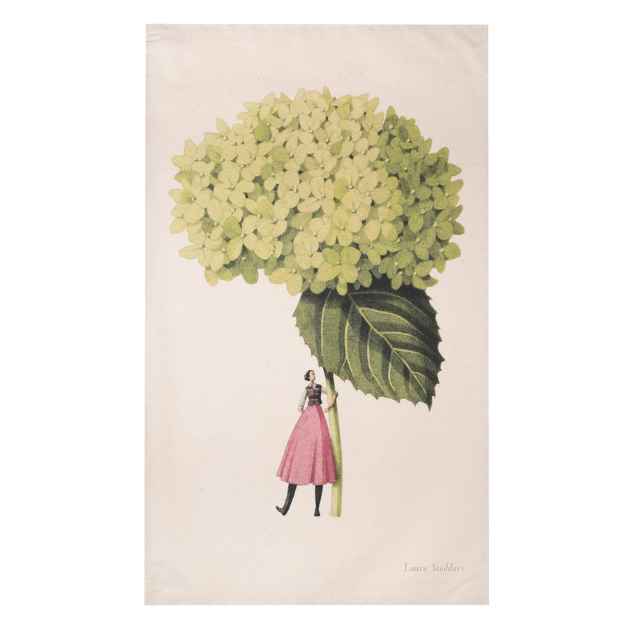 Beige tea towel with an illustration of a woman in a pink skirt holding an oversized green hydrangea. 