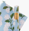 Blue wrapping paper sheets with white illustrated hydrangeas, against a white background.