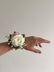 Hand displaying a corsage made in white and pink flowers.