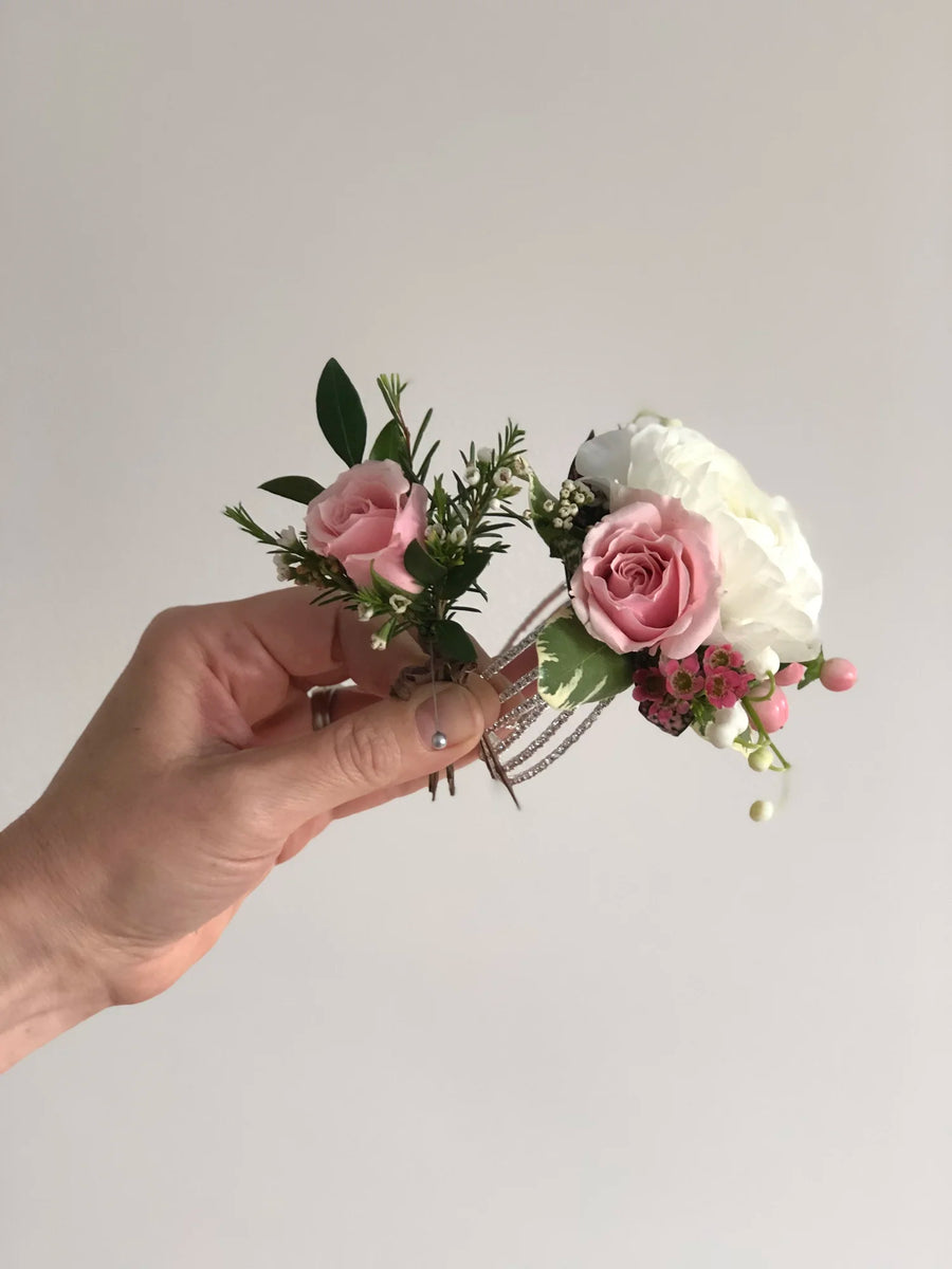 Hand holding matching boutonniere and corsage in pink and white flowers.