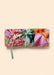 Rolled-up lavender jewelry roll with a vibrant floral and botanical pattern in purple, pink, green, and orange, tied with a sage green ribbon. 