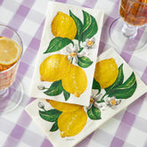 Napkins with lemon design on a purple checkered tablecloth with glasses of tea.