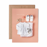 Pink greeting card with baby clothes and toys, with the words "Hello little gal".