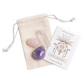 Beige pouch with rose quartz, amethyst, and quartz lying on top of it. A card with the Cast of Stones logo and the text "Love & Happiness Crystals and Stones" sits next to it against a white background.