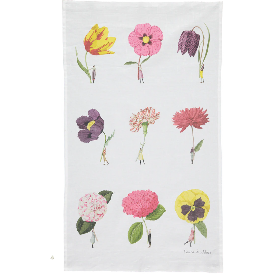 A white tea towel featuring a printed grid of nine colorful flowers, including tulips, poppies, and hydrangeas, with tiny figures standing beside each bloom. 