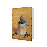 Orange card with a painting of a bluebird witting on a cup overflowing with blueberries. The text above reads "My cup runneth over. Psalm 23:5".