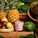 Candle sitting in the middle of passionfruit, guava, and pineapple. 