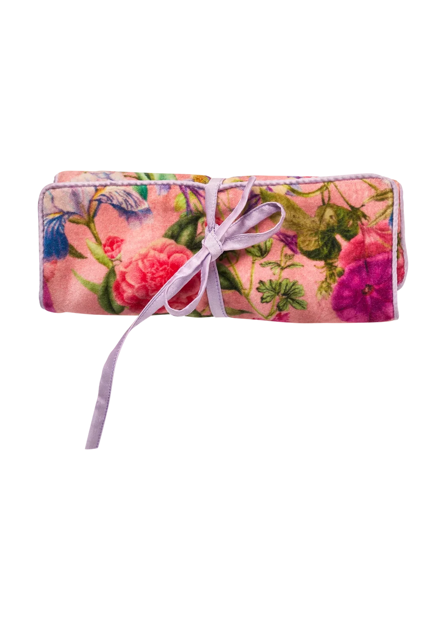Rolled up pink jewelry roll with a floral pattern in pink, purple and reens, tied with a lavender ribbon.