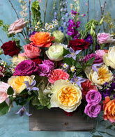 Close up shot of funeral piece in bright colors, in a wooden box.