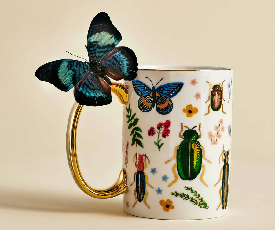 Mug with insect and floral design, featuring a butterfly on the handle against a beige background