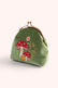 A small green velvet coin purse with a gold kiss-lock clasp and embroidered red-and-white mushrooms, pink flowers, and green leaves on the front, set against a light cream background.