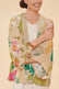 Woman wearing a cream kimono with a large-print tropical floral pattern, against a beige background