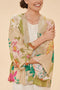 Woman wearing a cream kimono with a large-print tropical floral pattern, against a beige background