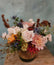 A floral arrangement made in a traditional muted autumn color palette, in a vase with a pumpkin-orange ribbon wrapped around the vase.