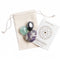 Beige pouch with flourite, amethyst, and hematite lying on top of it. A card with the Cast of Stones logo and the text "Wisdom & Guidance Crystals and Stones" sits next to it against a white background.
