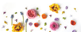 A flat lay of flower heads, including tulips, muscari, roses, ranunculus, and hydrangea, on a plain white background. 