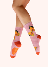 Light pink and orange socks with monarch butterflies, against a white background.