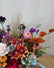 Close up of a moody fall-colored floral bouquet. Mums, red roses, straw flower and orange beech are among the flowers in the arrangement.