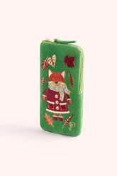 A green zip-around sunglasses case featuring an embroidered fox in a red coat and scarf, surrounded by autumn leaves, on a light cream background.