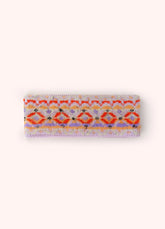 A headband with a geometric orange, purple and gold pattern on it, against a light background.