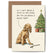 Greeting card of a yellow dog with a stick laying next to it. A Christmas tree can be seen in the background. The dog has a speech bubble above it that says "So I can't bring a stick in the house, but you can bring a whole tree?"