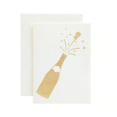Ivory greeting card with a gold foil cutout of a champagne bottle popping.