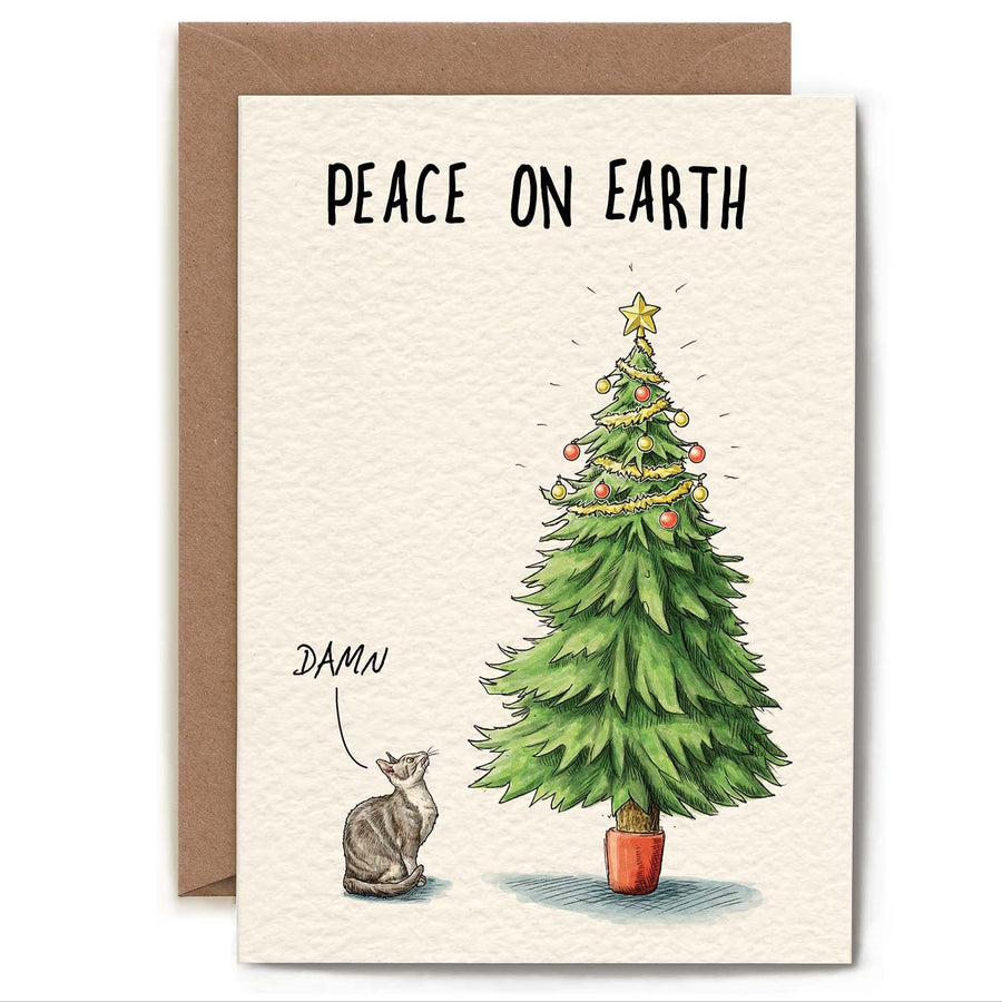 Greeting card with an illustration of a grey and white cat standing next to a Christmas tree that's decorated on the top third, out of the cat's reach. The card reads "Peace on Earth", and the cat has a speech bubble above its head that says "Damn".
