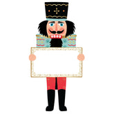 A paper table setting of a nutcracker dressed in a blue top and red pants.