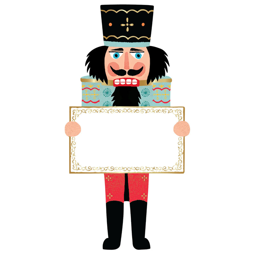 A paper table setting of a nutcracker dressed in a blue top and red pants.
